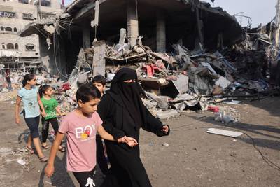 A woman and children walk past a house destroyed in Israeli strikes on Al Shatee camp in Gaza city. AFP