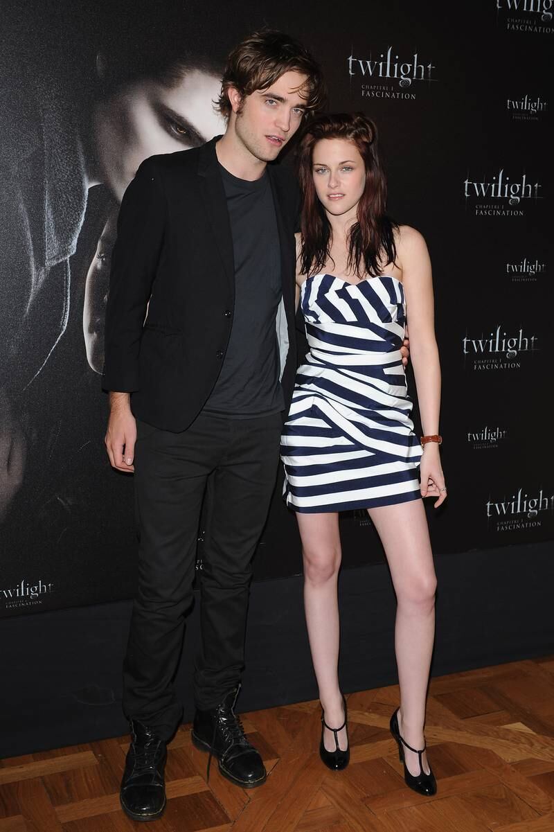 Robert Pattinson and Kristen Stewart, in a striped strapless dress, attend a photocall for 'Twilight' on December 8, 2008 at Hotel Crillon in Paris, France.