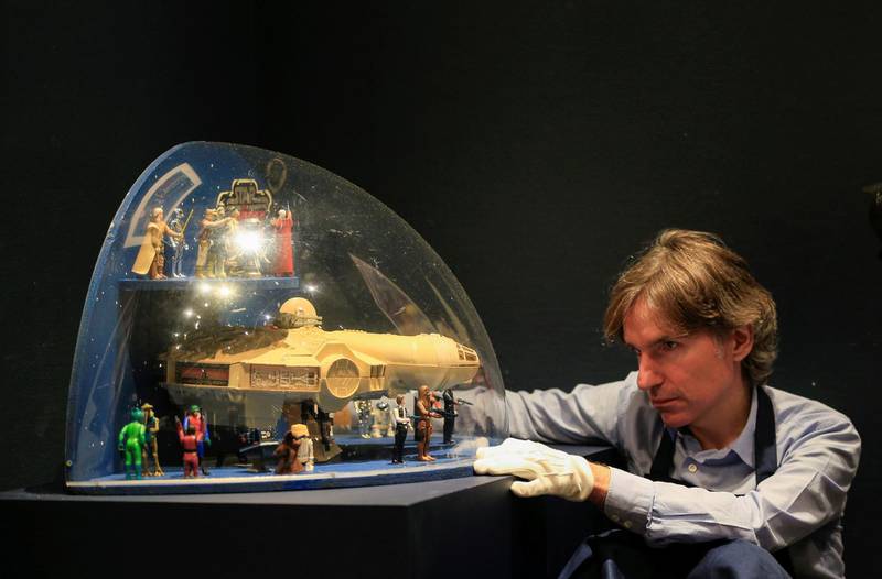 A Sotheby's employee poses with a "The Empire Strikes Back" Toy figures and a Millenium Falcon toy shop display from 1980, estimated at £7,000-£10,000, during a photocall at Sotheby's in London. Reuters