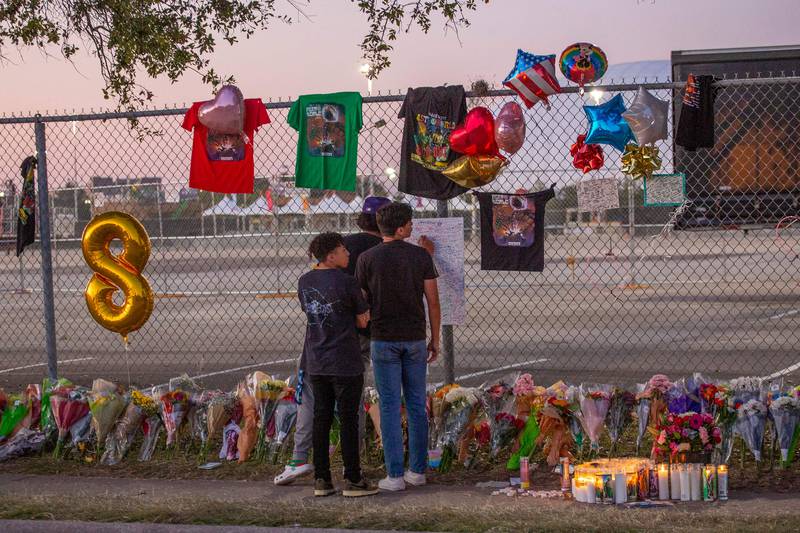 Local high school friends who attended the Travis Scott concert, Isaac Hernandez and Matthias Coronel, both 17, watch Jesus Martinez sign a remembrance board at the memorial. AFP