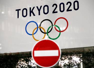 A banner for the upcoming Tokyo 2020 Olympics is seen behind a traffic sign, following an outbreak of the coronavirus disease (COVID-19), in Tokyo, Japan, March 23, 2020. REUTERS/Issei Kato