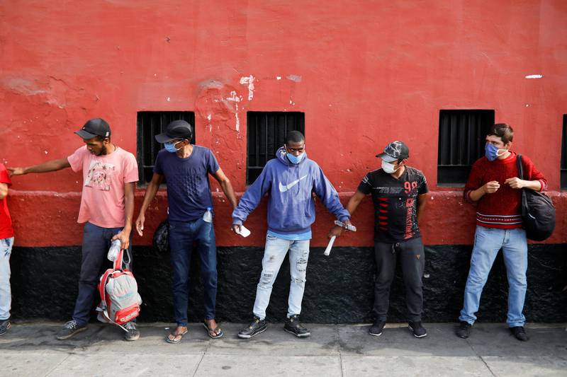 Homeless people use their arms to measure a safe distance from each other while waiting for a medical examination before entering the Plaza de Acho bullring, which the Peruvian government is retooling into a homeless shelter as part of its response to the spread of coronavirus disease (COVID-19), in Lima, Peru. REUTERS