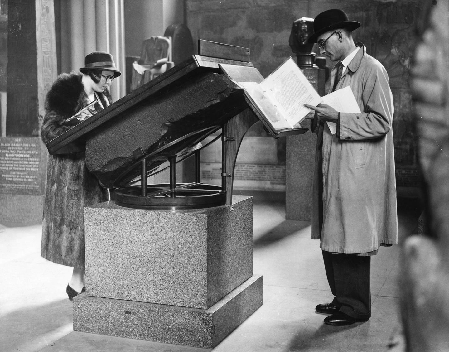 14th September 1932:  Visitors reading information concerning the Rosetta Stone, from the top of the Stone itself, in the Egyptian Gallery at the British Museum.  (Photo by Fox Photos/Getty Images)