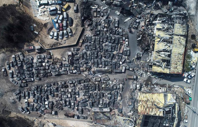 Burnt vehicles filling a junkyard after being hit by a massive forest fire are seen from above. Yonhap via AP