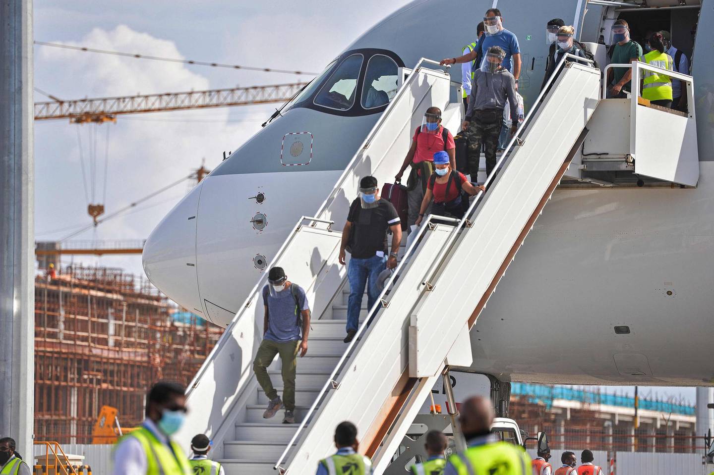 Passengers disembark from a Qatar Airways aircraft upon their arrival at the Velana International Airport in Male on July 15, 2020. The Maldives formally reopened for tourists on July 15 with a water salute for a commercial airliner bringing holiday makers to the upmarket destination where foreigners will get free coronavirus tests. / AFP / Ahmed SHURAU
