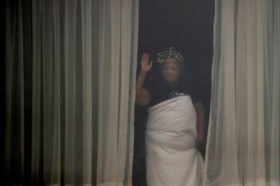 A woman waves through the window of the Radisson Blu Edwardian hotel. AP Photo