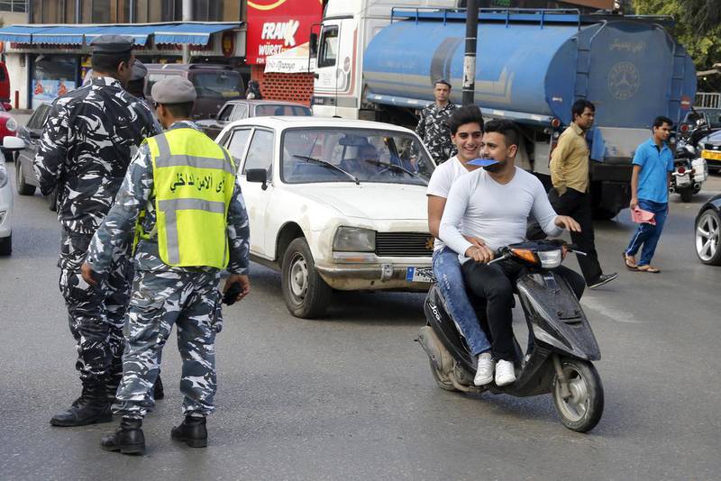 Men ride a scooter without helmets past policemen controlling traffic in Beirut on April 22, 2015, the day a strict new traffic law took effect in Lebanon. Mohamed Azakir / Reuters