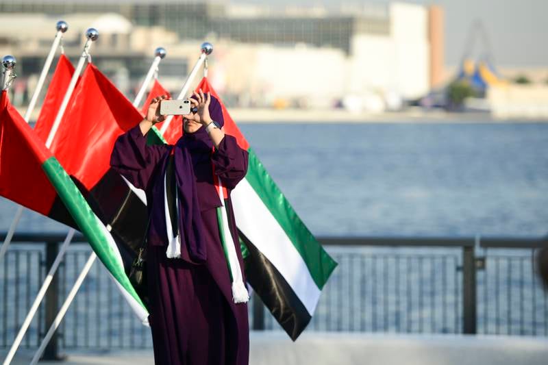 A visitor take photos against a backdrop of UAE flags
