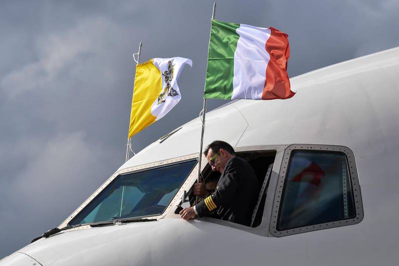 Italian captain Andrea Gori adjusts the Italian national flag next to the Vatican flag, as the Pope's plane prepares to take off. AFP