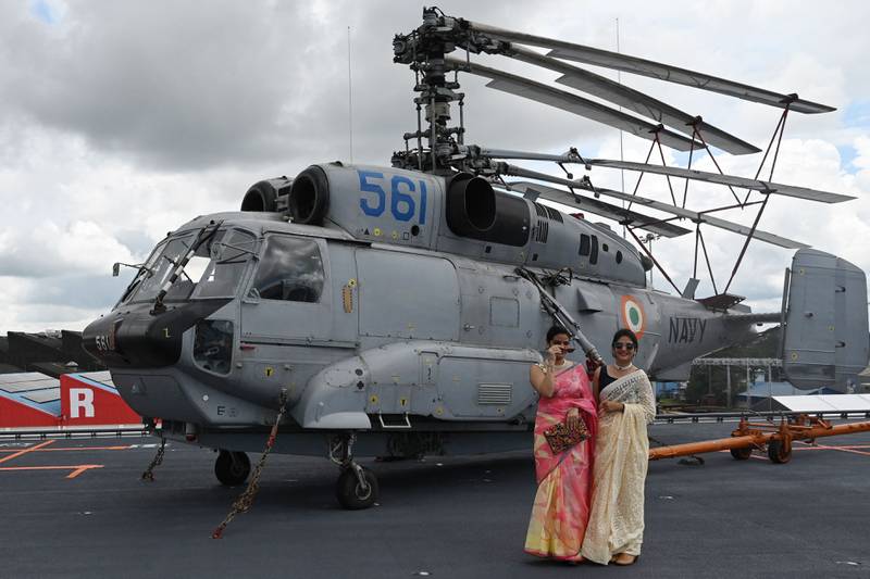 Women stand next to a Komoho Helicopter on the deck of the 'Vikrant'. AFP
