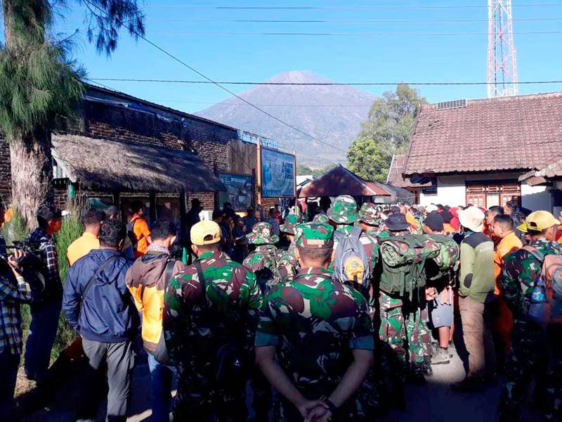 Indonesian soldiers and rescue team gather to prepare for evacuating tourists from Mount Rinjani, seen in the background, at Sembalun in East Lombok, Indonesia, Monday, July 30, 2018. A strong and shallow earthquake early Sunday killed more than a dozen people on Indonesia's Lombok island, a popular tourist destination next to Bali, officials said. (AP Photo)