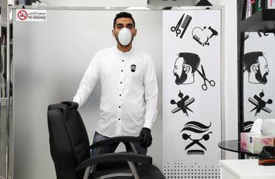 DUBAI, UNITED ARAB EMIRATES , March 25 – 2020 :- Taha Hussein, 34 years old from Egypt working as a hairdresser at the Hair & Beard gents salon near the Mövenpick Ibn Battuta Gate Hotel in Dubai. He is married and has two daughters. He told as a safety measure in these circumstances whenever someone is coming to the salon they are using disposable capes and blades for their customers. There is a sanitizer placed at the cash counter for the customers as a preventive measure against coronavirus in Dubai. He is using facemask, gloves, washing and sanitizing his hands regularly for his safety. He said customer appreciate his services in these circumstances.  (Pawan Singh / The National) For Unsung Hero of UAE Photo Feature