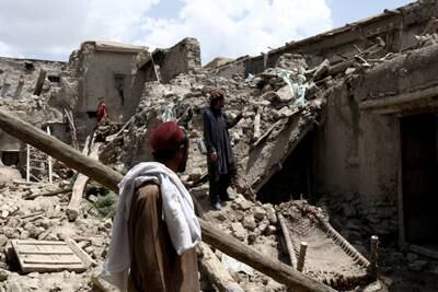 Afghan men stand on the debris of a house that was destroyed by an earthquake in Gayan. Reuters