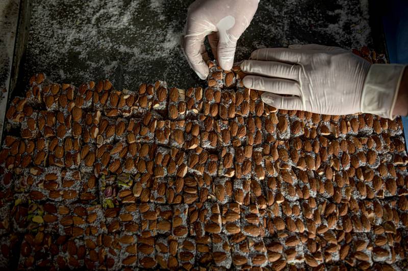 A factory worker covers the sweets in powdered sugar. 