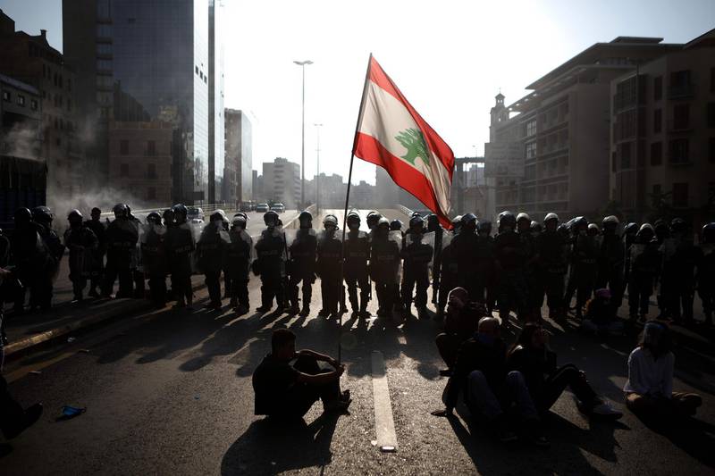 Lebanese protesters wave the national flag in front of riot police in the capital Beirut.   AFP