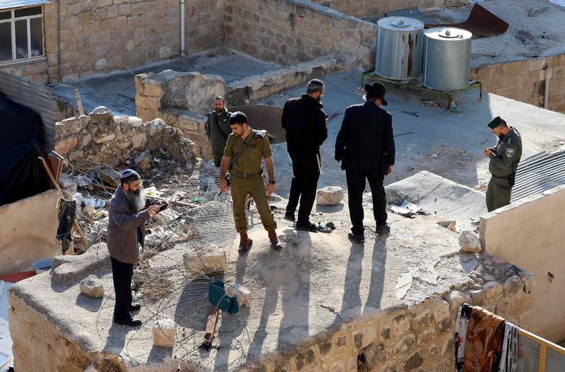 Israeli soldiers and settlers stand over a Palestinian house near the Ibrahimi mosque, also known as cave of patriarchs, in the West Bank city of Hebron. Local reports state the Israeli army informed the owners of the house that the army will take over the house.  EPA