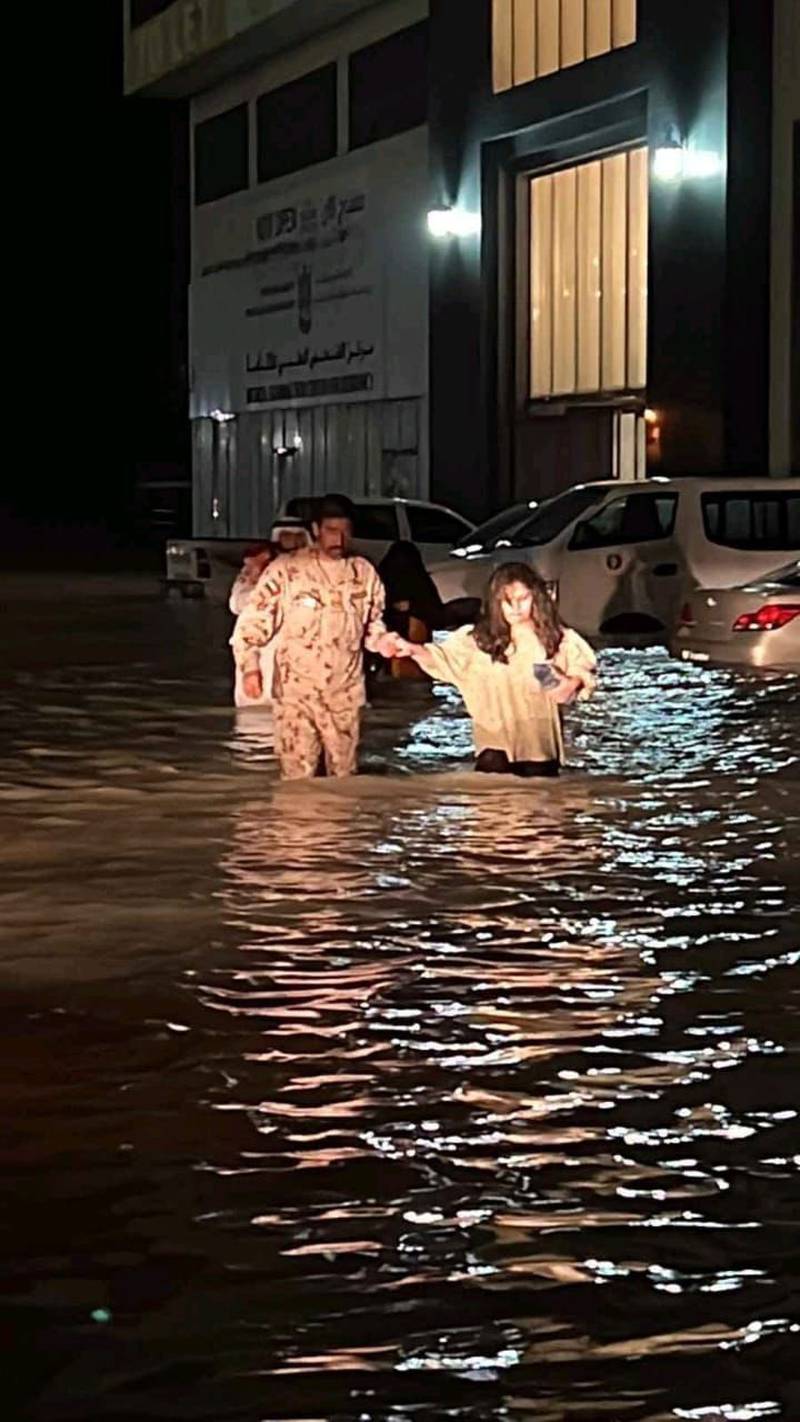 Servicemen help residents wade through floodwaters in the Northern Emirates. 