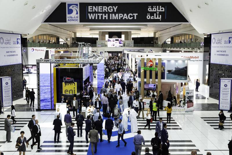 Delegates pass exhibitor's stands at the Abu Dhabi International Petroleum Exhibition & Conference (ADIPEC) in Abu Dhabi, United Arab Emirates, on Tuesday, Nov. 13, 2018. OPEC’s secretary-general, energy ministers from Saudi Arabia to Russia, CEOs at oil majors from Total SA, BP Plc and Eni SpA, and officials from Middle Eastern energy giants such as Abu Dhabi’s Adnoc have gathered to sign deals and discuss oil, gas, refining and petrochemical issues. Photographer: Christopher Pike/Bloomberg