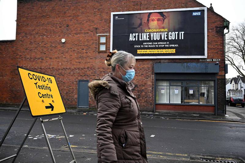 A pedestrian walks past a coronavirus information poster near a temporary testing facility at the Walsall Arena & Arts Centre in Walsall. AFP