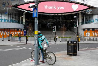 A food delivery courier carrying a Deliveroo, operated by Roofoods Ltd., backpack stands near a message thanking Britain's National Health Service in Birmingham, U.K. Bloomberg