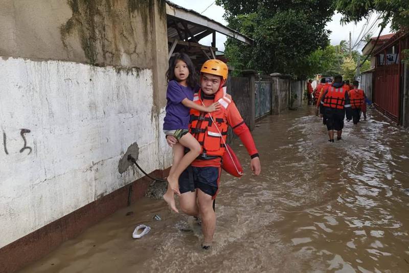 A rescuer carries a girl amid flooding caused by Tropical Storm Nalgae in Zamboanga, southern Philippines. AP