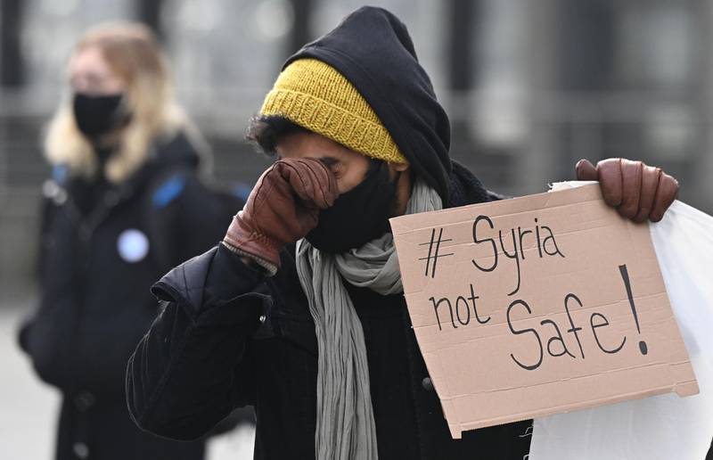 A demonstrator wipes his face during a protest against deportation to Syria in Berlin on December 13, 2020.  / AFP / Tobias Schwarz
