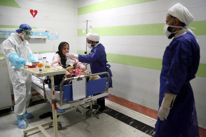 A cleric assists a medic treating a patient infected with the new coronavirus, at a hospital in Qom, south of the capital Tehran, Iran.  AP