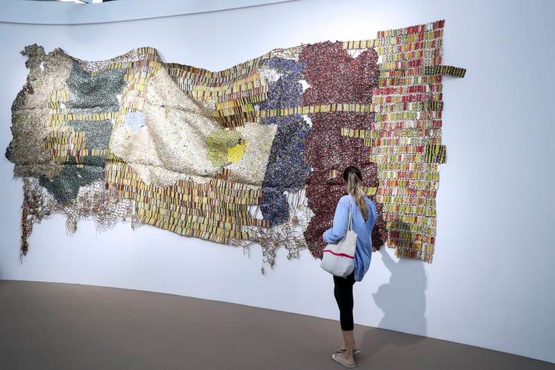 A visitor at Efie Gallery with El Anatsui's 2021 work 'TT'. Khushnum Bhandari / The National