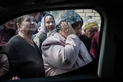 A woman covers her ears from the sound of mortar fire as people queue to collect pensions from a postal delivery van that reached the frontline despite the ongoing conflict in Mayaky, eastern Ukraine, on May 6. AFP