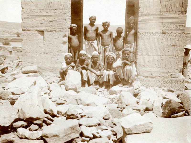 Ten local boys pose at the rock-strewn entrance of the temple of Dendur.