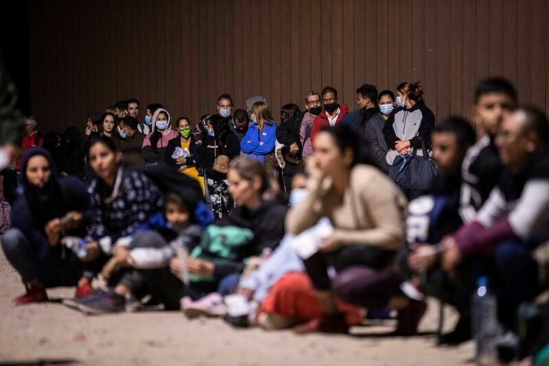 Migrants wait in line to have their identities checked by US border patrol officers before they can get into a bus for a processing center after they crossed the border between the United States and Mexico through an opening in the wall, in Yuma, Arizona, 28 October 2022 (issued 29 October 2022).   EPA / ETIENNE LAURENT
