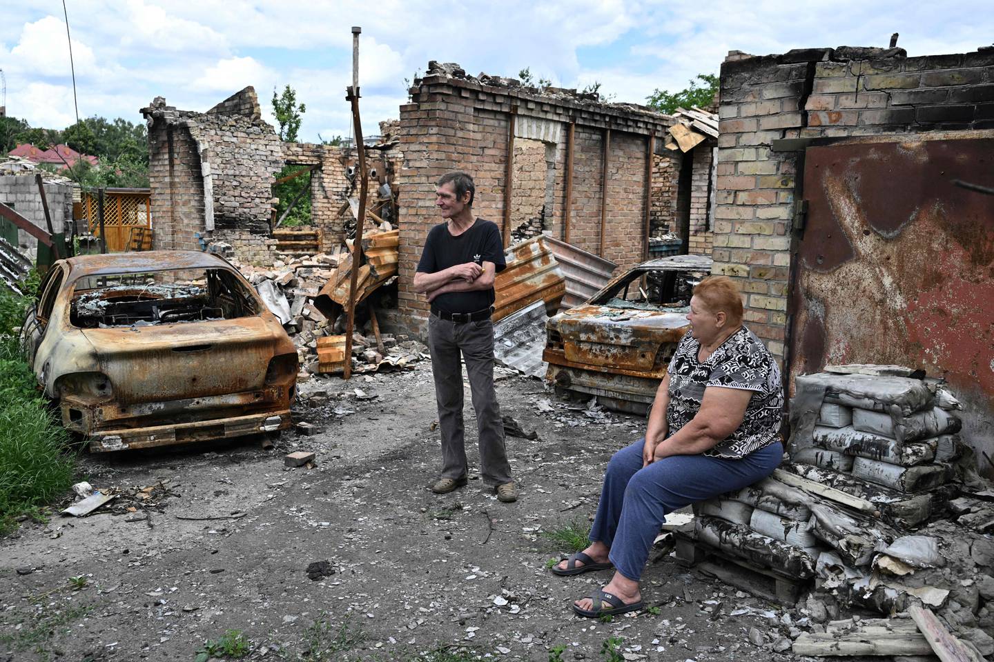 Residents wait for humanitarian aid next to a destroyed house in the town of Bucha. AFP