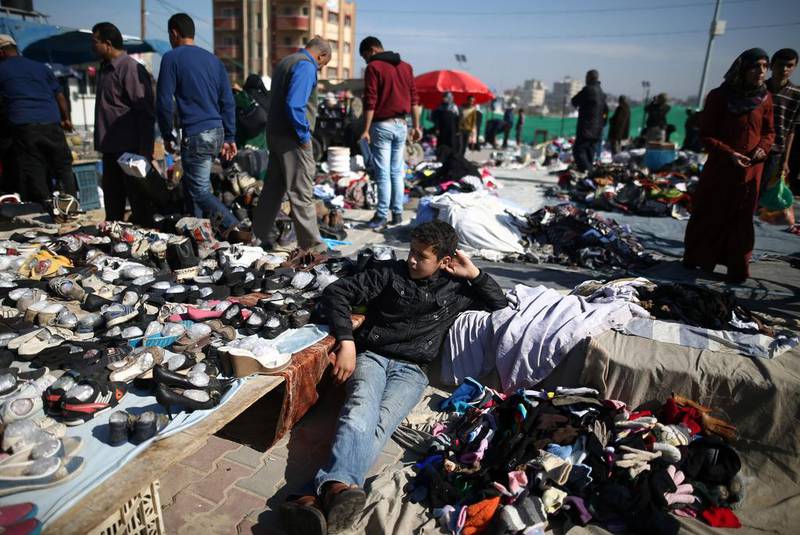 A Palestinian boy sits amidst used clothes and items at the weekly flea market in the Nusseirat refugee camp, central Gaza Strip, on February 29, 2016. / AFP / MOHAMMED ABED