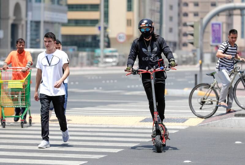 Abu Dhabi, United Arab Emirates, August 13, 2019.  People using E-scooters at the Al Wahda mall area, downtown Abu Dhabi.  --Pedestrians try to beat the heat while using umbrellas.Victor Besa/The NationalSection:  NAFOR:  StandaloneVictor Besa/The NationalSection:  NAFOR:  Standalone