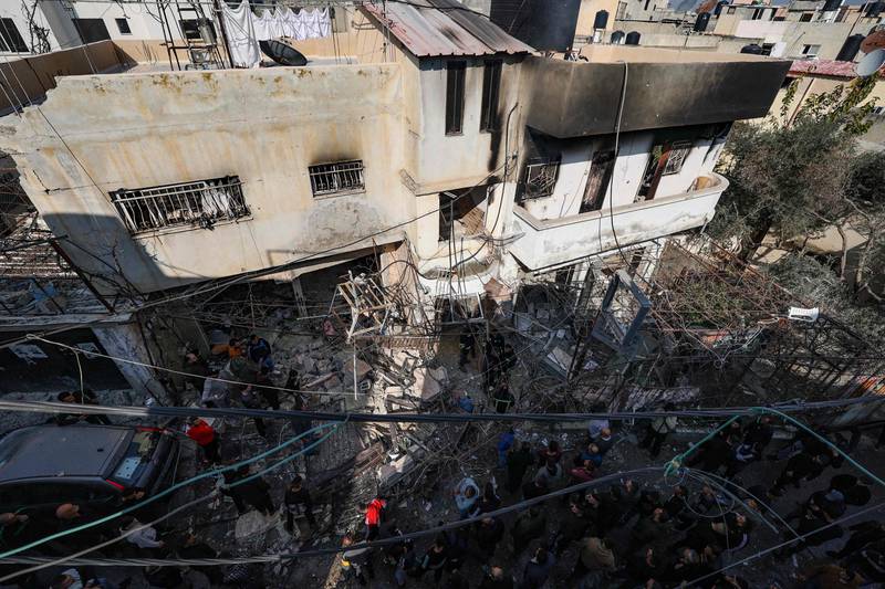 People gather around a building damaged and burned by Israeli troops during the raid. AFP