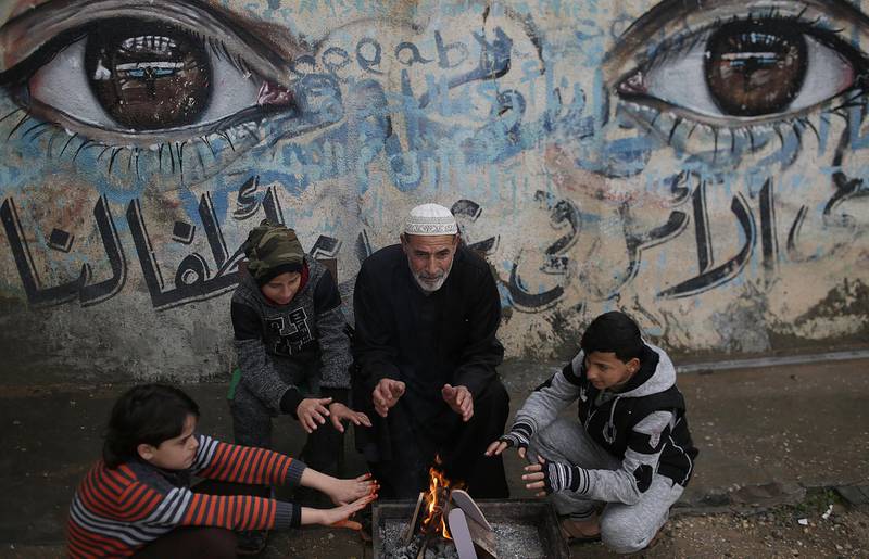 A Palestinian grandfather and his family warm themselves by fire outside their house on the street of Beit Hanun town northern Gaza Strip, during stormy weather in Gaza Strip. Mohammed Saber / EPA