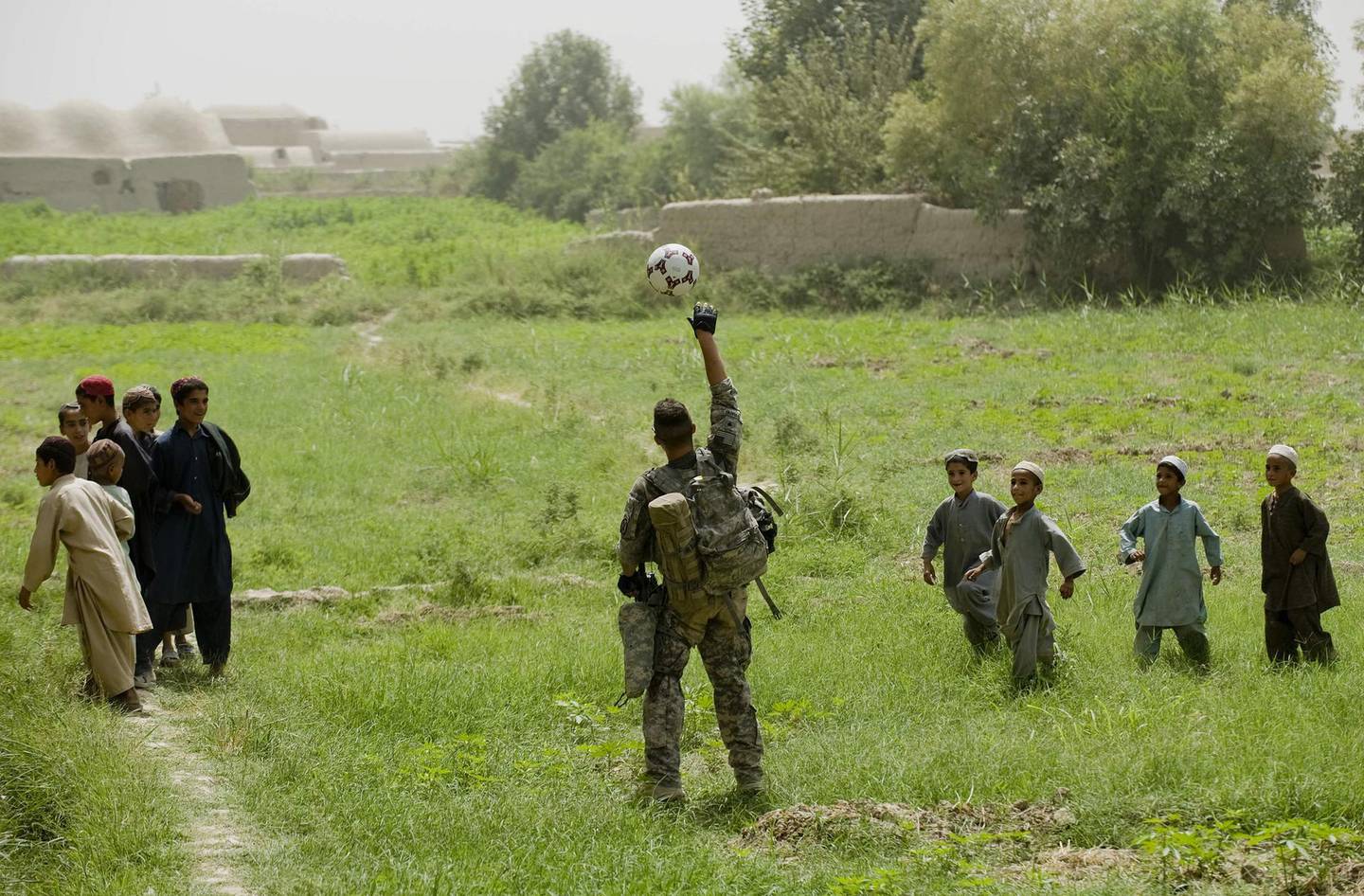 (FILES) In this file photo a US soldier (C) from 1st Platoon Bravo Troop of 1st Squadron, 71st Cavalry plays with a soccer ball with Afghan children during a patrol in Dand district of Kandahar Province in Afghanistan on July 24, 2010.   US President Joe Biden will formally announce on April 14, 2021 the withdrawal of all US troops from Afghanistan before this year's 20th anniversary of the September 11 attacks, finally ending America's longest war despite mounting fears of a Taliban victory, officials said. The drawdown delays only by around five months an agreement with the Taliban by former president Donald Trump to pull troops, amid a growing consensus in Washington that little more can be achieved.
 / AFP / MANPREET ROMANA

