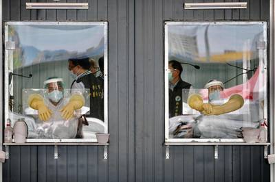 Medical personnel are seen behind their sealed work areas at a swab test screening area for the Covid-19 in New Taipei City. AFP