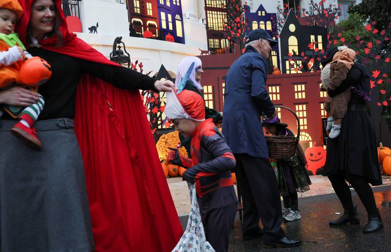 Children in costumes and their adult family members receive candy from Mr and Ms Biden at the White House. Reuters