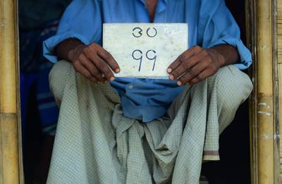 This photograph taken on July 20, 2018 shows Rohingya refugee Jalal Ahmed with his old house number plate in Jamtoli refugee camp in Ukhia, in the Bangladesh border area near Myanmar. - A wistful smile passed across Jalal Ahmed's face as he turned the piece of faded tin over his hands, tracing the outline of the Burmese characters painted on its surface. "This is the numberplate from my house. In our country, every house had one of these," the 52-year-old Rohingya refugee from Myanmar told AFP in the doorway of the cramped bamboo shanty where he lives in destitution with his family in southern Bangladesh. (Photo by MUNIR UZ ZAMAN / AFP) / To go with BANGLADESH-MYANMAR-ROHINGYA-UNREST-REFUGEE-OBJECTS,FEATURE by Nick PERRY