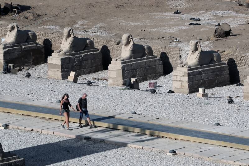 People walk along the Avenue of Sphinxes.