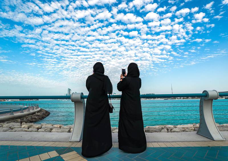 Two women photograph the view from Abu Dhabi's Corniche. Victor Besa / The National