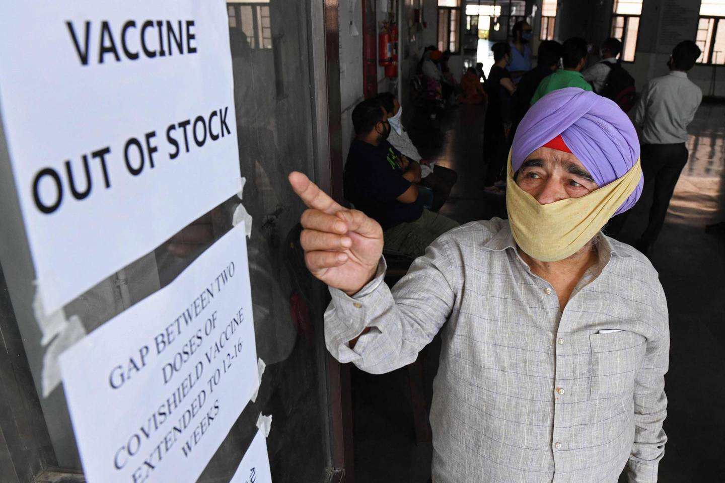 A man gestures to notices displayed in a civil hospital indicating about the Covid-19 coronavirus vaccine being out of stock in Amritsar on May 17, 2021. / AFP / Narinder NANU
