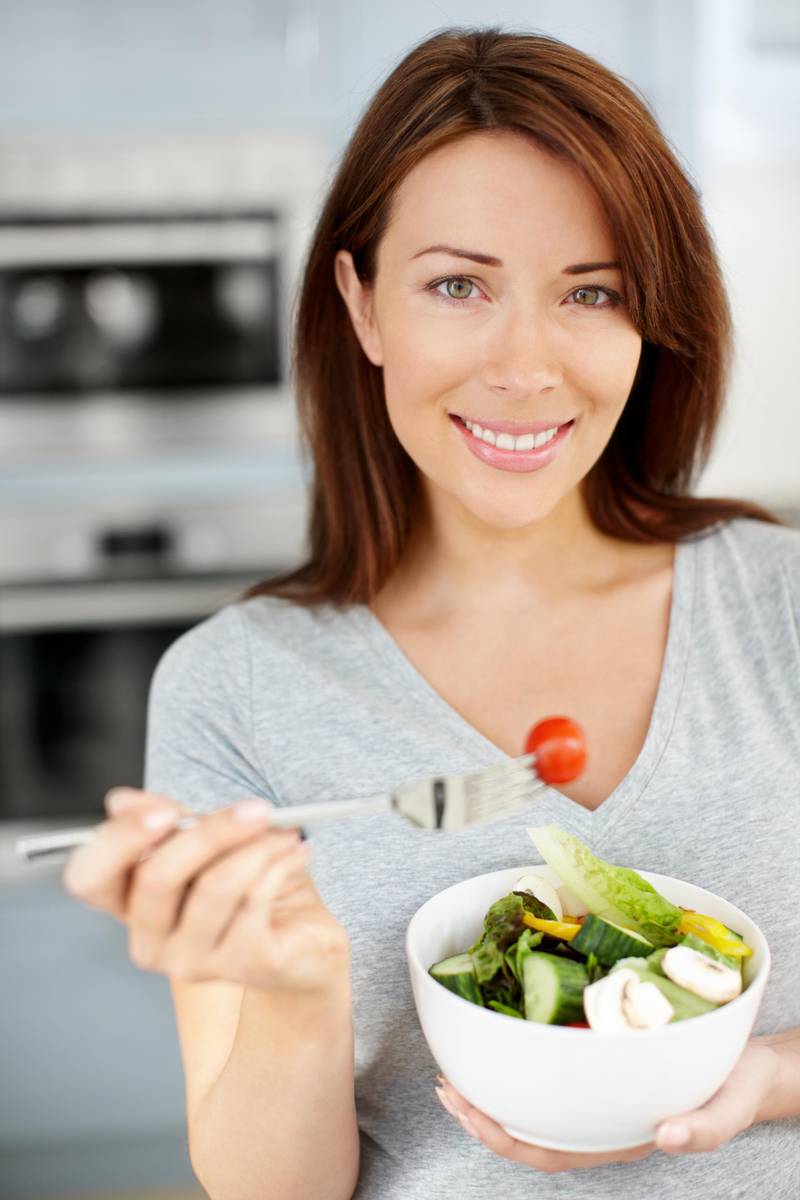 Closeup portrait of an attractive young woman eating a healthy salad as she stands in her kitchen (Getty Images) *** Local Caption ***  hl16ju-tips-eat-p23.jpg