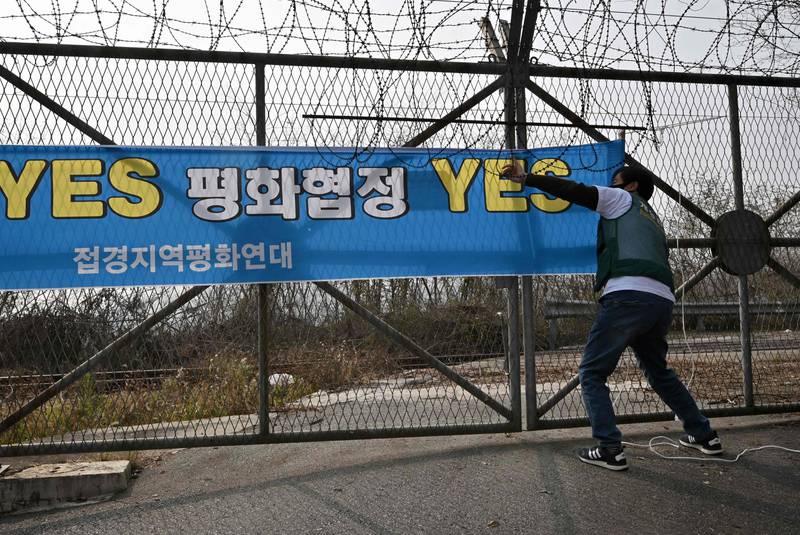 A pro-unification activist puts up a banner reading 'Yes end-of-war declaration, Yes peace treaty' on a fence near the Demilitarised Zone dividing the two Koreas. AFP