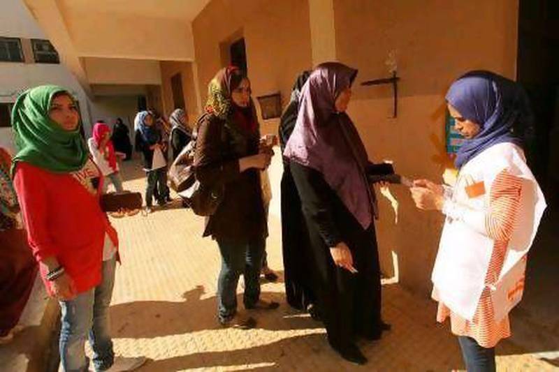 An electoral worker, right, verifies the identity of voters at a polling station during the National Assembly election in Benghazi today. Reuters