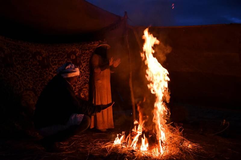 A Bedouin family gather around a fire after a heavy rainstorm.