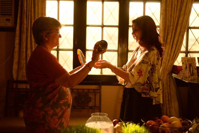 A traditional welcome performed by Parsis during Nowruz. The host Roshan Mehri (left) places a few drops of rose water onto the guest's palms as way to wish them a new year. As part of tradition, the host will also hold up a mirror to the guest in a symbolic gesture that hints toward a clear and bright future. Mobeen Ansari