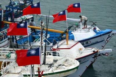 A fisherman raises a Taiwanese national flag as several dozen fishing boats set out from the Suao harbor, northeastern Taiwan, to the disputed islands in the East China Sea.