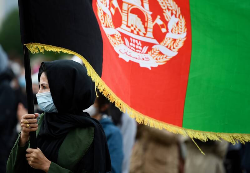 A person holds the flag of Afghanistan during a protest against support for the Taliban, in Berlin, Germany.